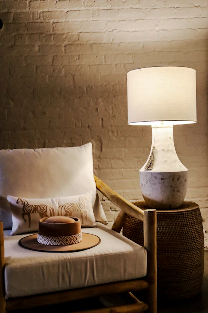 A cozy living room corner featuring a sleek modern lamp casting warm light over a stylish wooden side table with decorative spoons displayed.