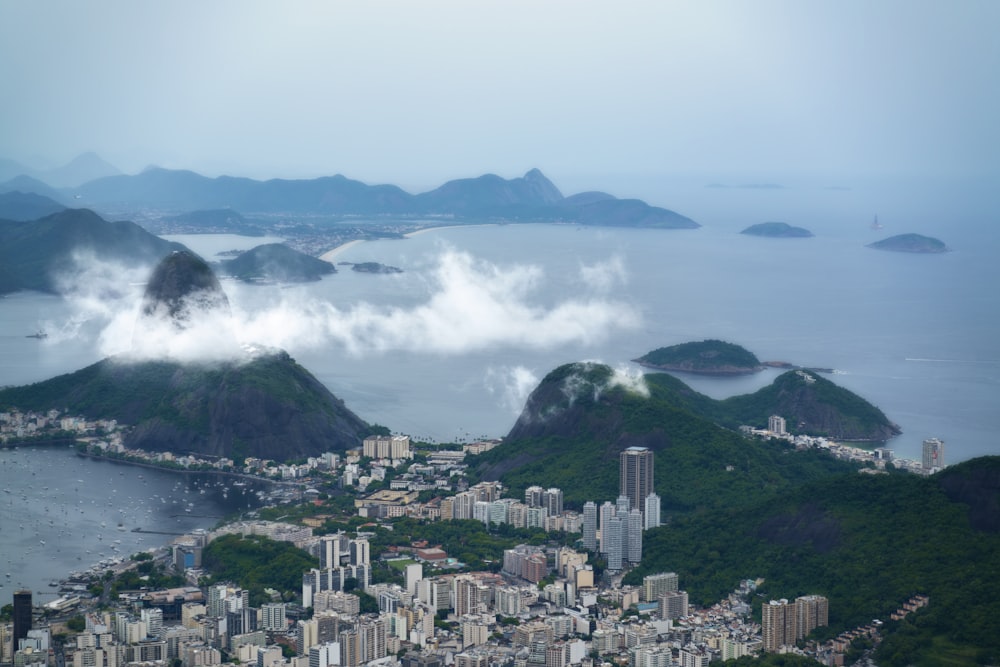 a city on a hill with a body of water and mountains in the background