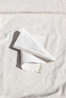 Close-up of finely crafted French linen napkins folded on a beige tablecloth.