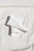 Close-up of a natural linen napkin folded elegantly on a rustic wooden table.