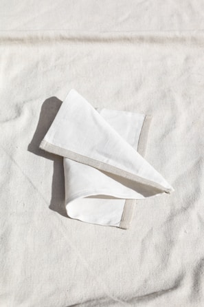 Close-up of finely crafted French linen napkins folded on a beige tablecloth.
