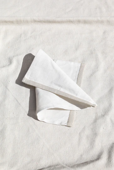 Close-up of a cream-colored dinner napkin with a delicate navy blue monogram embroidered in elegant script.
