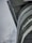 A modern architectural structure with its curved contours and steel elements set against a cloudy sky. The angle showcases the juxtaposition of the heavy concrete material and the open sky, with a streetlamp visible at the bottom left.