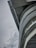 A modern architectural structure with its curved contours and steel elements set against a cloudy sky. The angle showcases the juxtaposition of the heavy concrete material and the open sky, with a streetlamp visible at the bottom left.