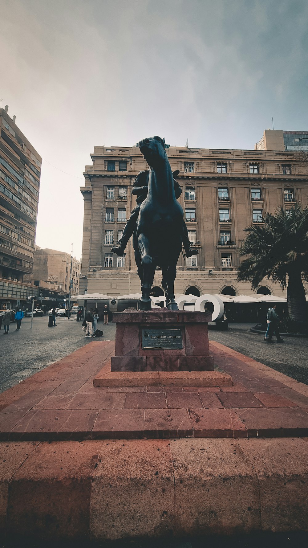 a statue of a person on a horse in a courtyard with buildings in the background
