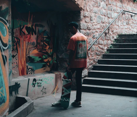 A complete skateboard setup resting against a graffiti-covered urban wall.