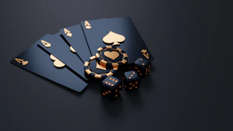 Black playing cards with gold aces, poker chips, and dice on dark surface
