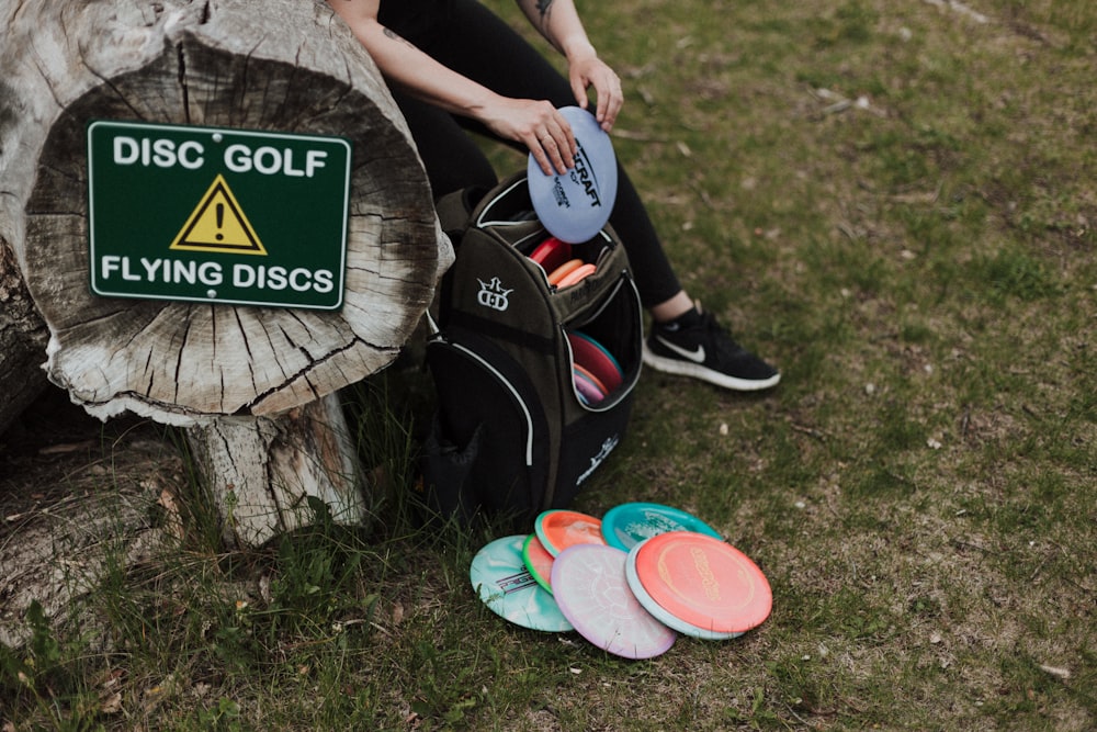 a person sitting on a tree stump with a backpack and a sign