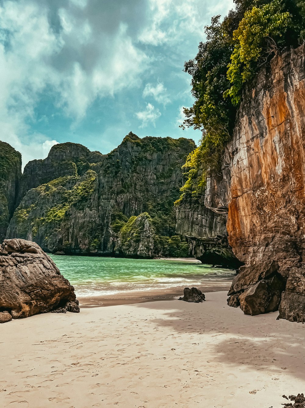 a beach with a body of water and large rocks