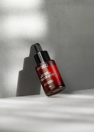 Close-up of a sleek black bottle of hydrating facial serum with a dropper on a dark background