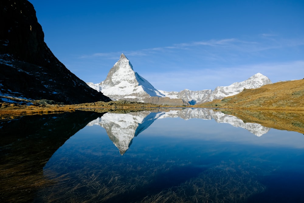 a body of water with snowy mountains in the background with Matterhorn in the background