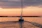Sailboat gliding peacefully on the calm waters of Baía de Todos os Santos during sunset with vibrant orange and pink sky.