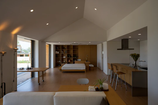 An open living area featuring concrete elements and oak wood furniture bathed in natural light.