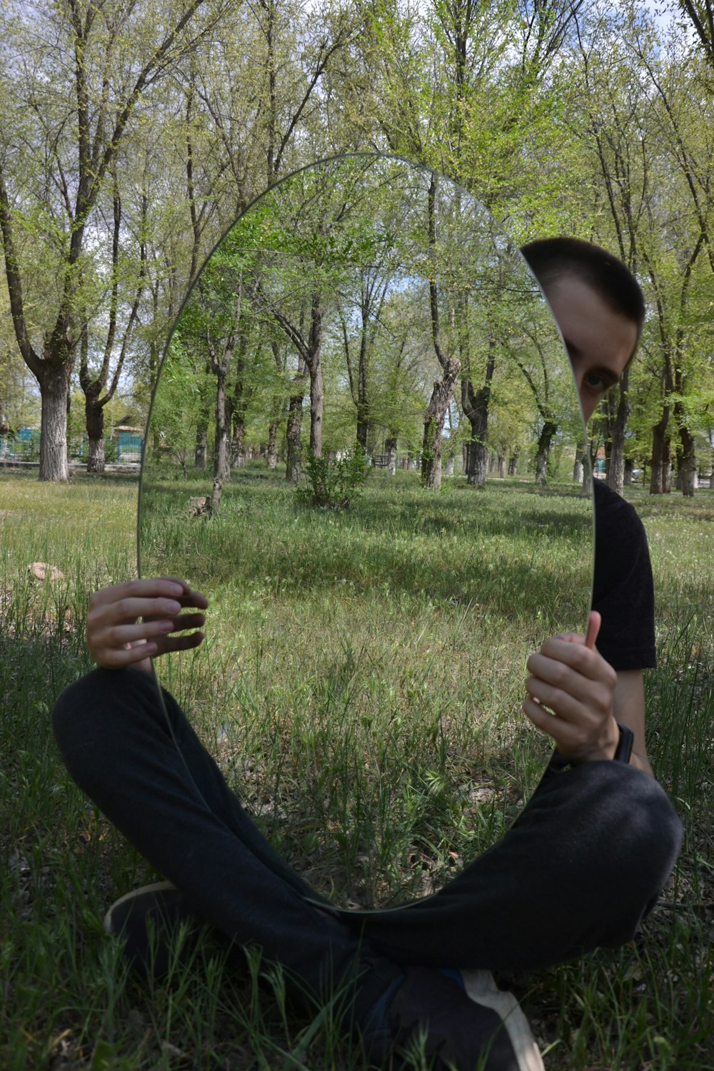 a person lying on their back in a grassy area with trees in the background