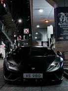 A classic Lamborghini Aventador in matte black under city lights.