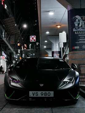 High-end Lamborghini parked under neon lights in a downtown setting.