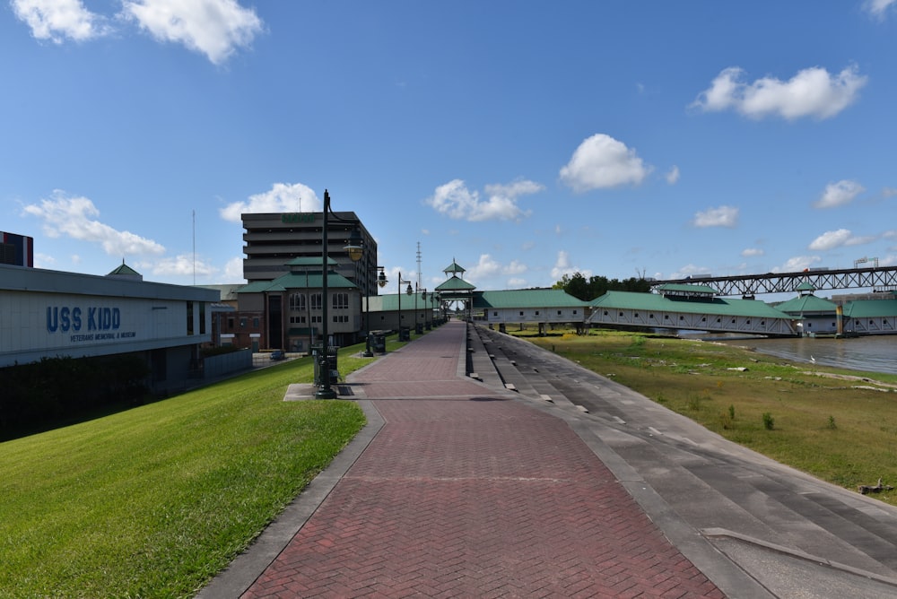 a brick walkway with a building and a bridge in the background