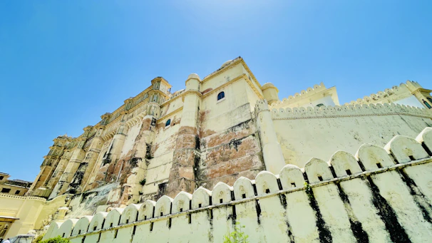 Majestic Rajasthan palace with golden sunlight highlighting intricate architecture under a clear blue sky.