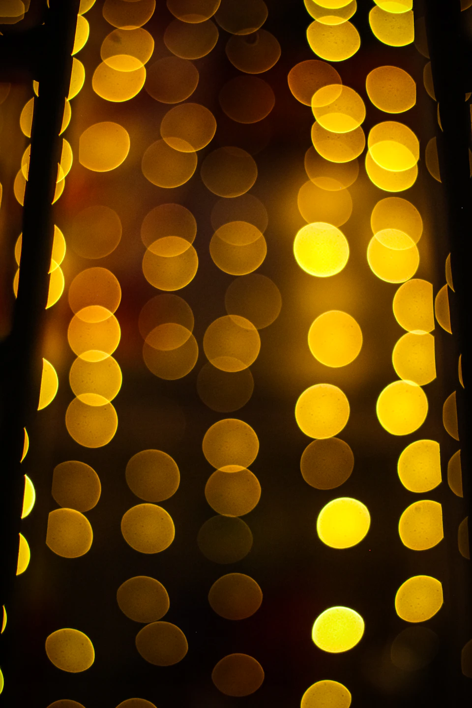 Close-up view of a grid-like pattern of yellow circles on a black background wall