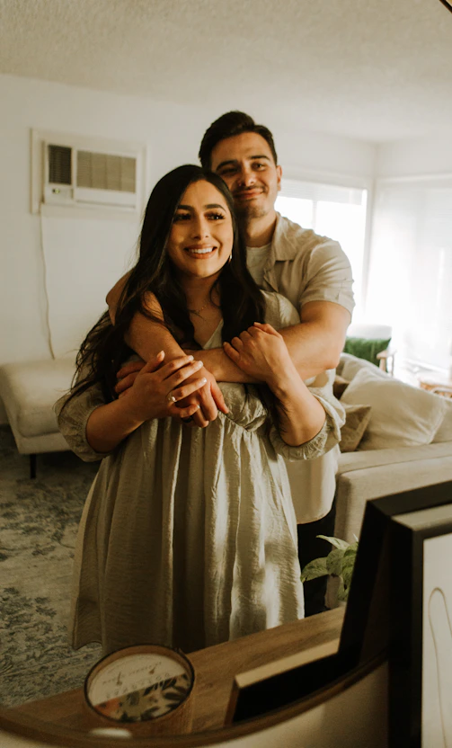 A warm, inviting photo of a couple holding hands in a softly lit room with burgundy and cream tones.