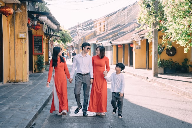 Uma família de quatro integrantes caminhando de mãos dadas e expressando alegria