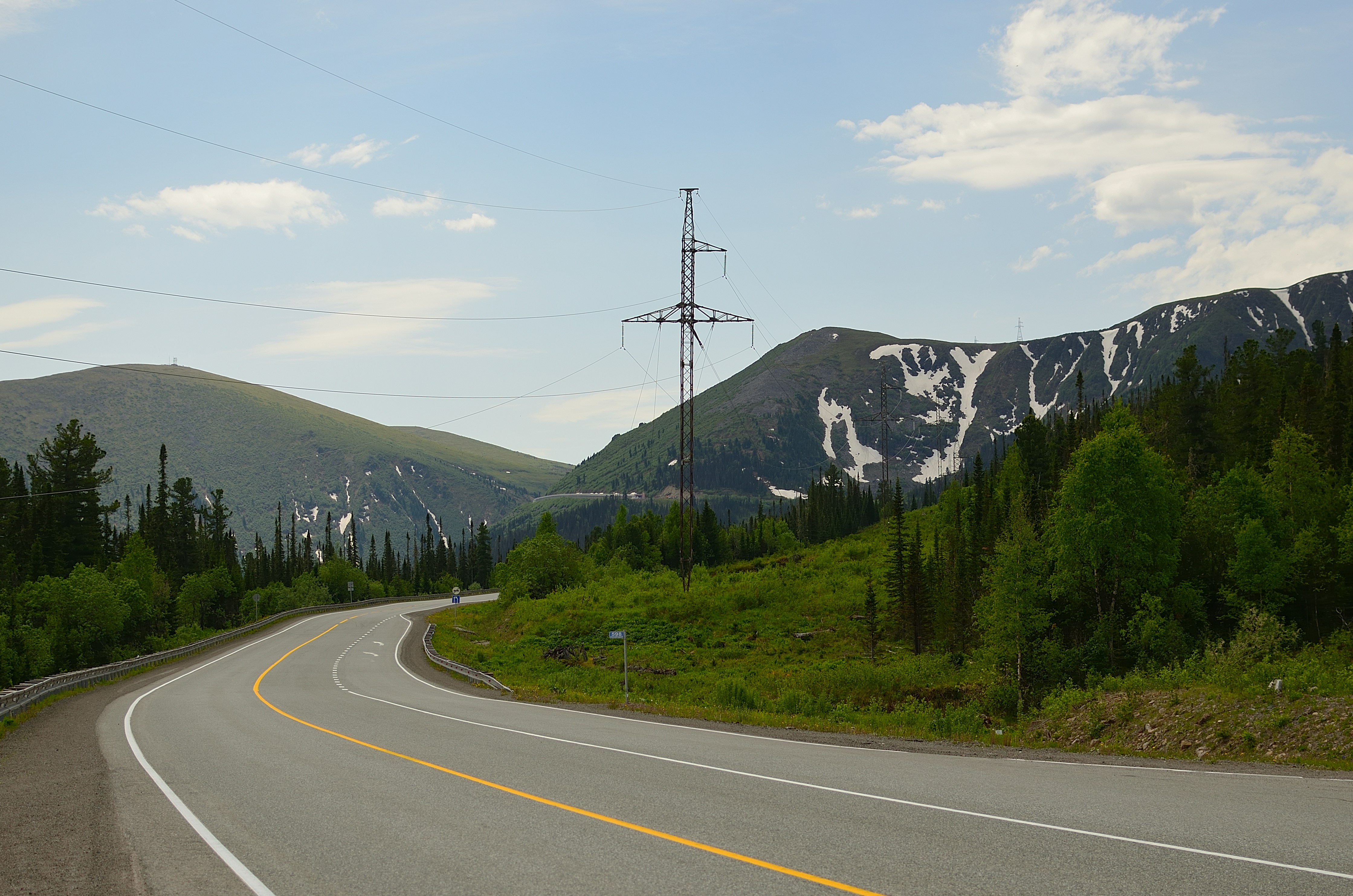 a road with trees and mountains in the background