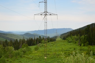 High-voltage transmission lines stretching across a green landscape towards a modern data center facility.