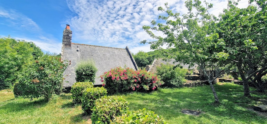 A serene outdoor stage set in a lush green garden with a historic house in the background.
