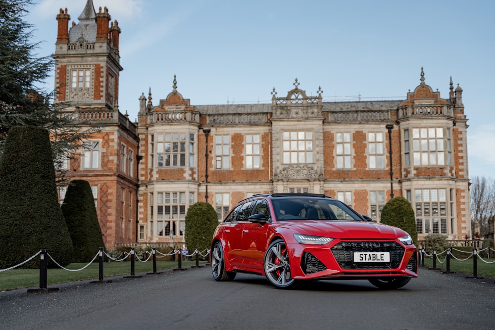 a red sports car parked in front of a large building with Crewe Hall in the background
