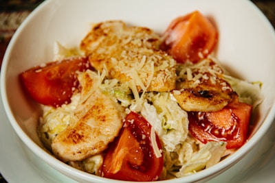 Bright red bowl filled with a colorful, fresh salad topped with grilled chicken strips