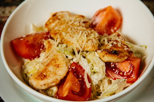 A vibrant bowl of colorful quinoa salad topped with grilled chicken and fresh herbs, showcasing a perfect balance of gains and grains.