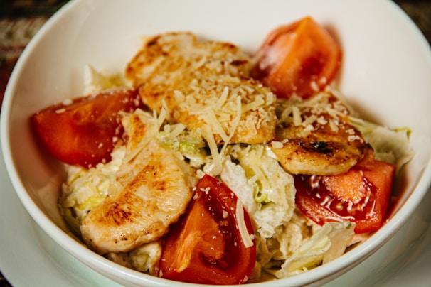 A vibrant bowl of fresh, colorful salad with grilled chicken and avocado slices.