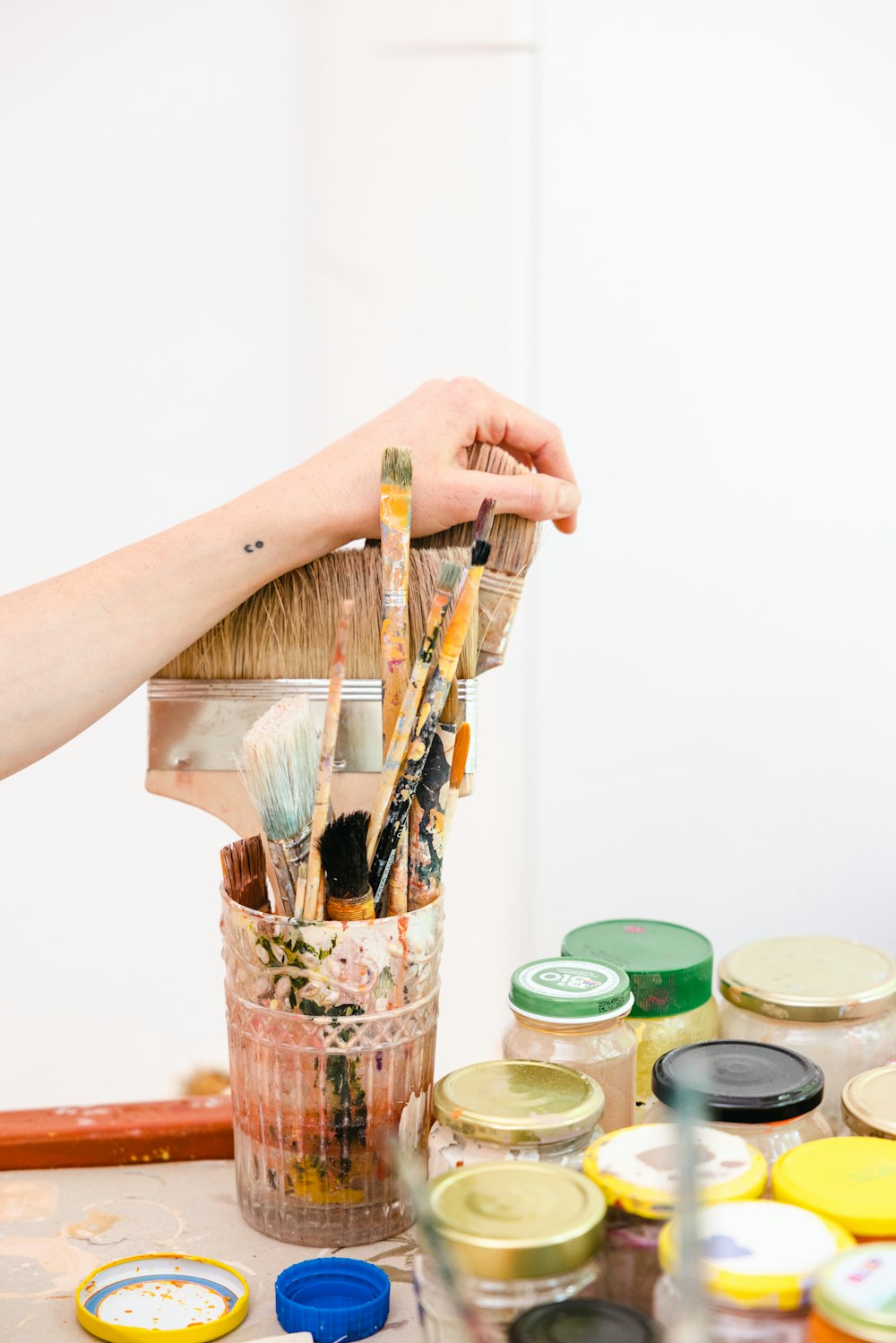 a hand holding a stick over a jar of food