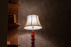 Bamboo table lamp with soft light, sitting on a rustic desk beside a stack of books.
