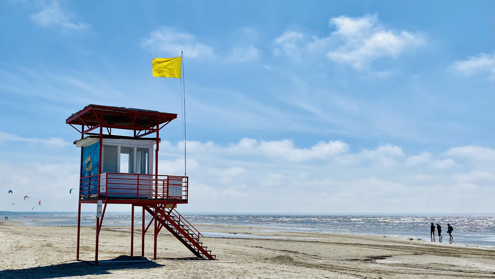 A red lifeguard tower on the wide sand of Pärnu beach