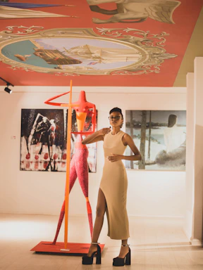 A stylish woman wearing a chic nude-toned dress from Delora Royale's premium collection, standing confidently in a softly lit boutique.