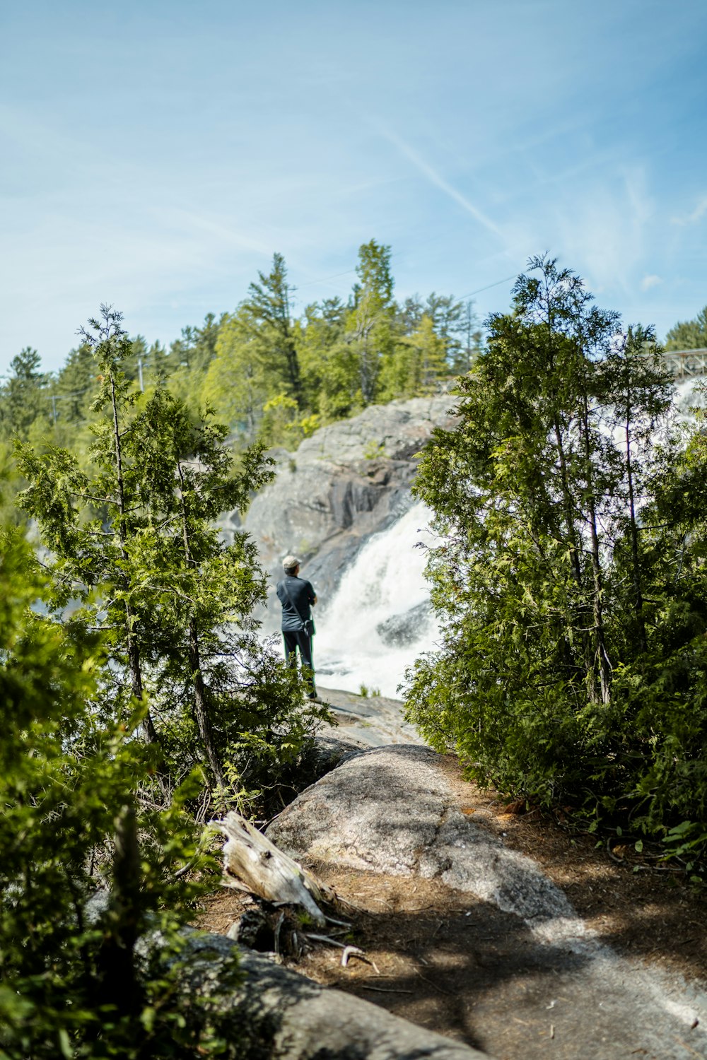 una persona in piedi su una roccia vicino a una cascata
