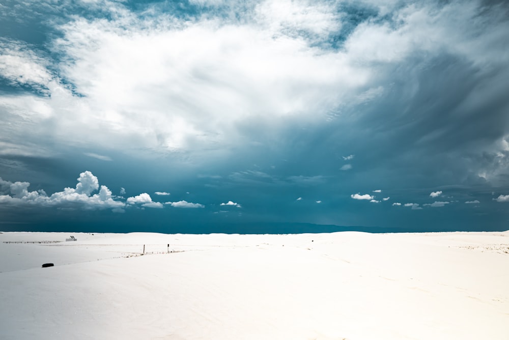 a snowy field with clouds in the sky