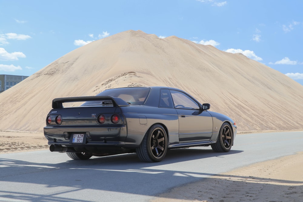 a car parked in front of a large sand dune