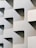 A building facade featuring an abstract, geometric design with repeating patterns of cut-out shapes. The structure is characterized by its minimalist aesthetic and uniform light-colored surfaces.