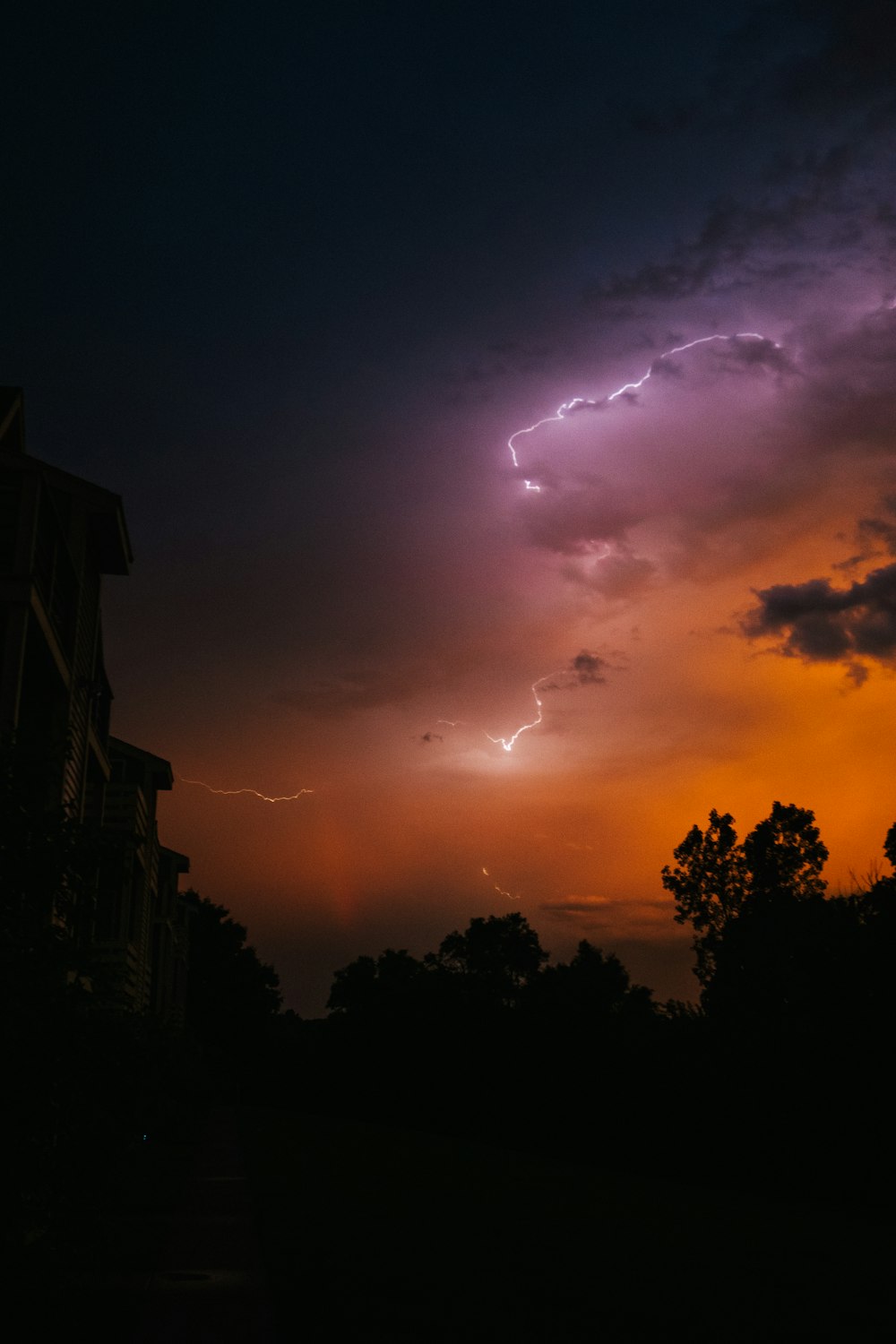 a sunset with lightning and trees