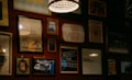 A wall adorned with various framed artworks and photographs, including images of a bicycle, inspirational quotes, and abstract designs. The lighting is warm and subtle, with a prominent hanging lamp creating a cozy atmosphere.