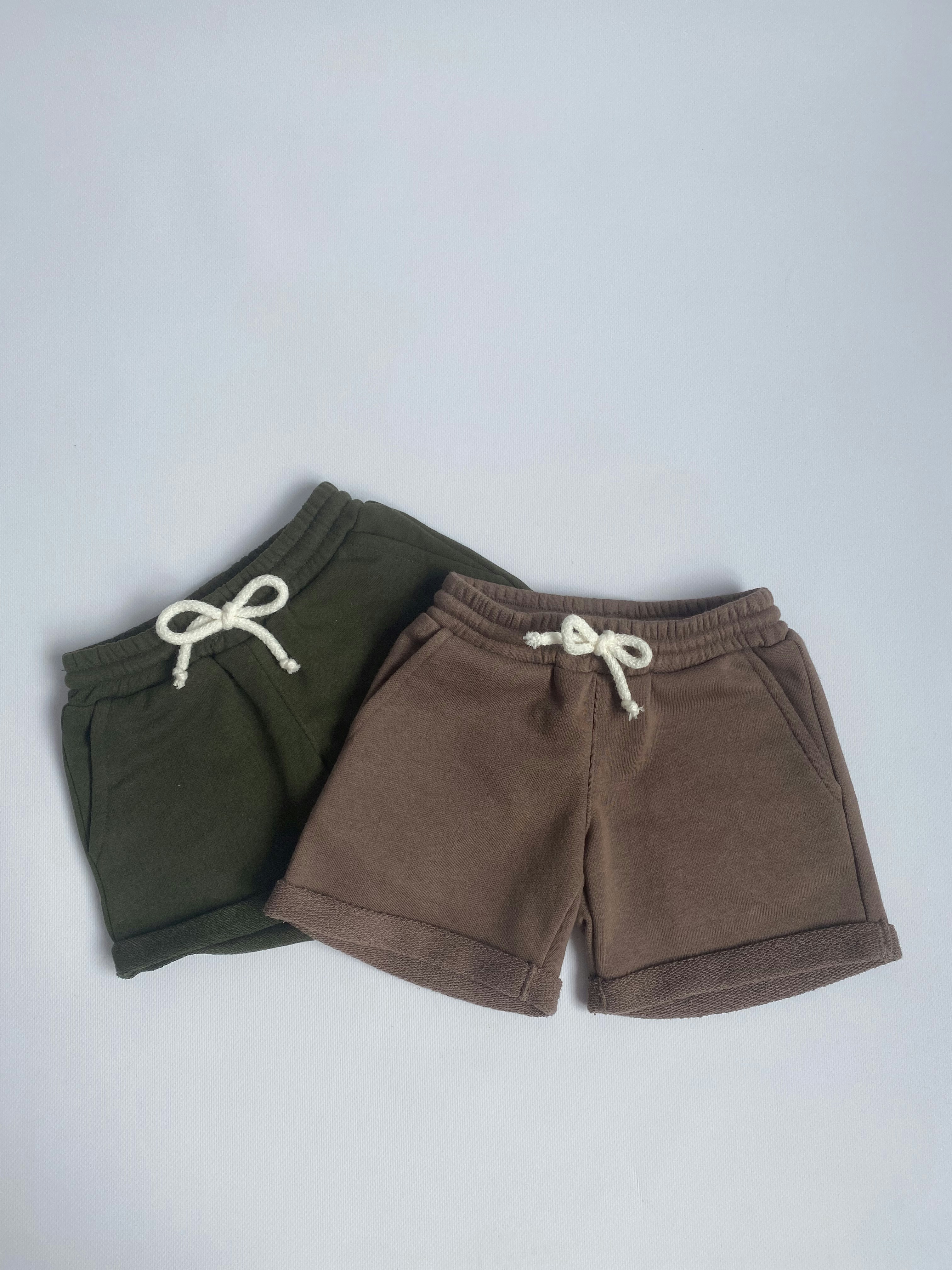 Casual trousers and shorts laid flat on white background, top-down bright shot