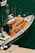 A bright orange rescue boat is moored at a dock, featuring several antennas and life-saving equipment. The boat's side is marked with the phrase 'Les sauveteurs en mer'. The surrounding water is a deep blue-green color, with another small boat visible partially in the background.