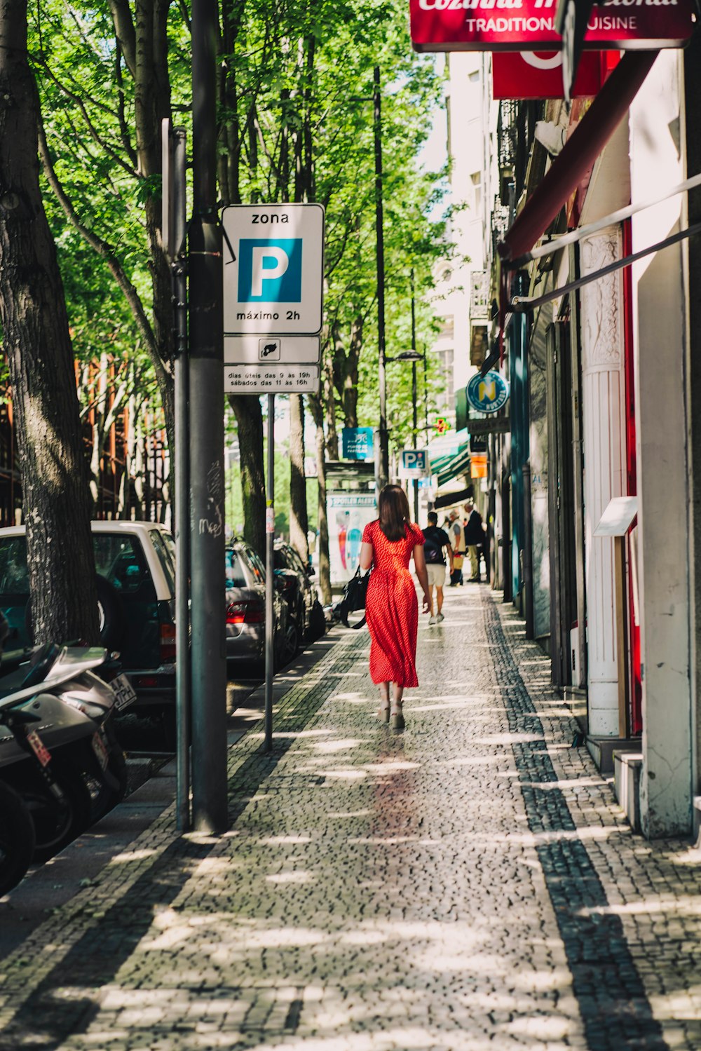 a person in a red dress walks down a sidewalk