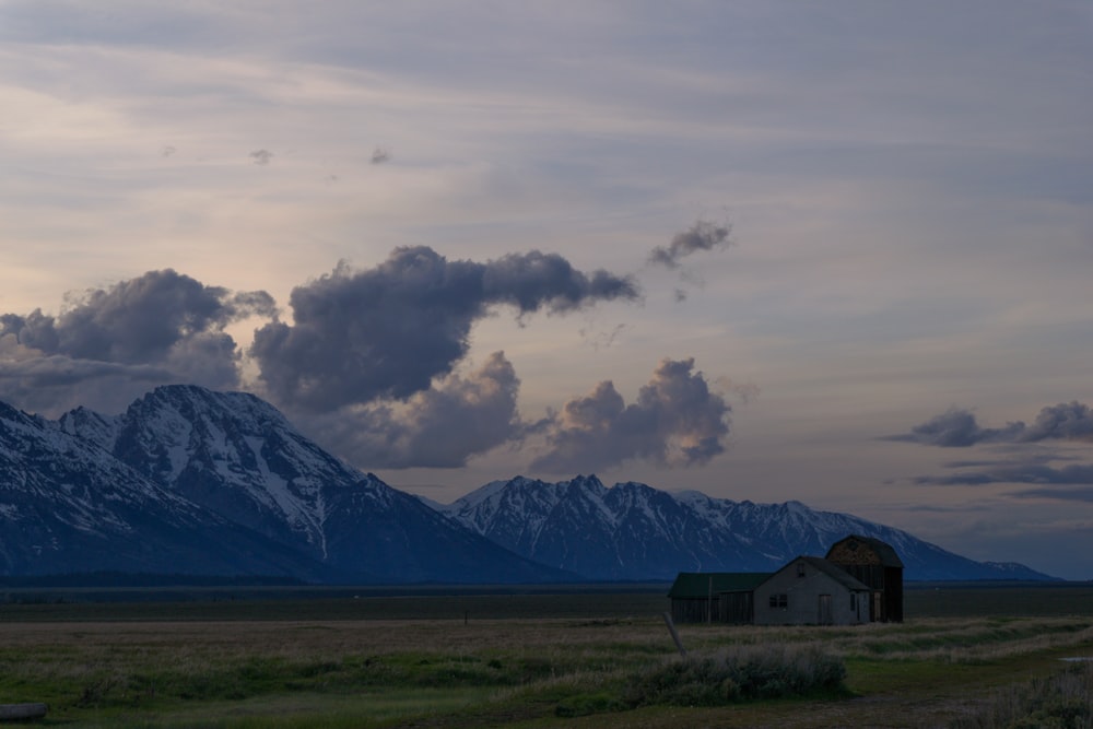 a house in a field with mountains in the background