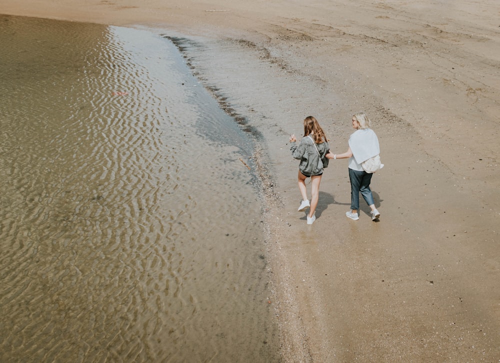 a couple of women walking on a beach