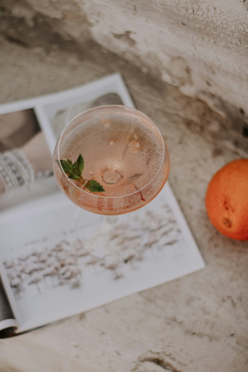 a glass of liquid next to a small orange on a counter