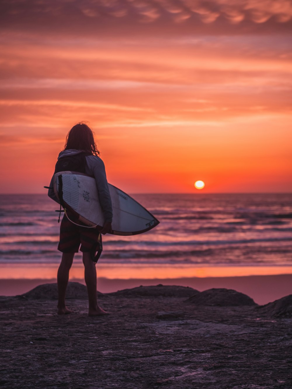 a person carrying a surfboard on a beach