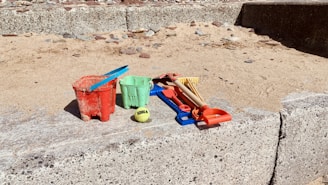 Colorful children's water play toys arranged on a sunny poolside deck.